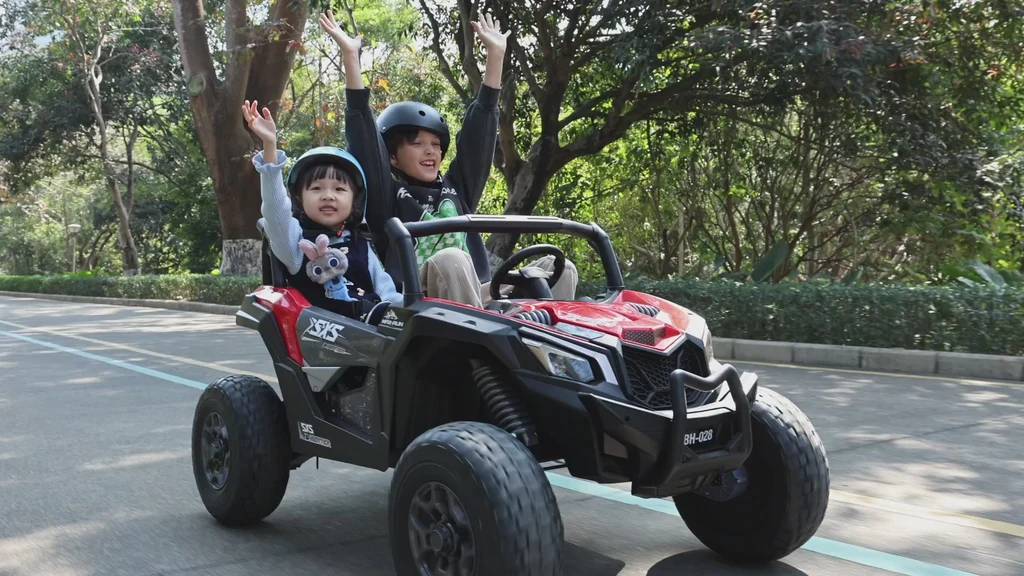 Kids driving a two-seater ride-on car on a paved path at a Lakeland, FL party