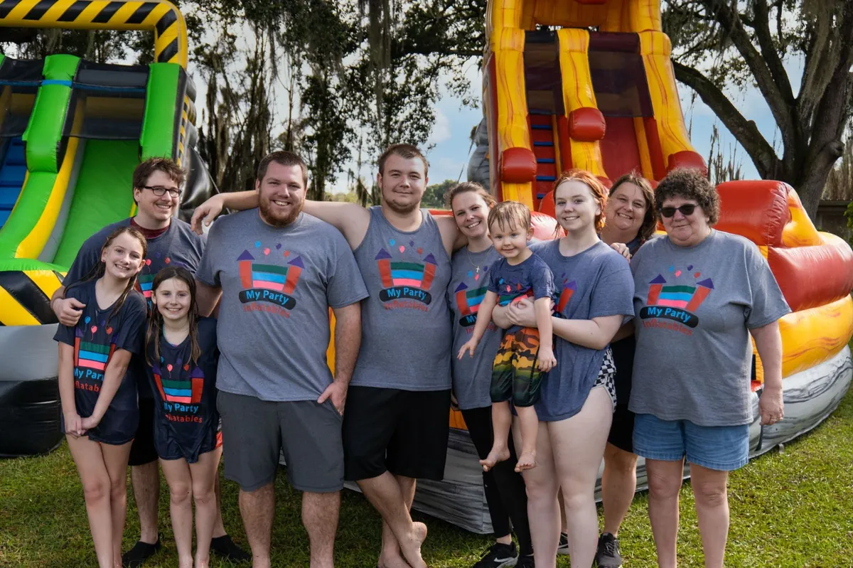 The My Party Inflatables family team in matching company shirts standing in front of water slides in Lakeland, Florida